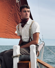 Man sitting on a sailboat with a sail in the background