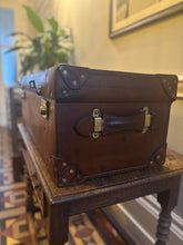 Brown leather suitcase on a wooden table with a decorative background