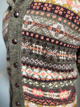 Close-up of a patterned sweater with buttons on a blurred background
