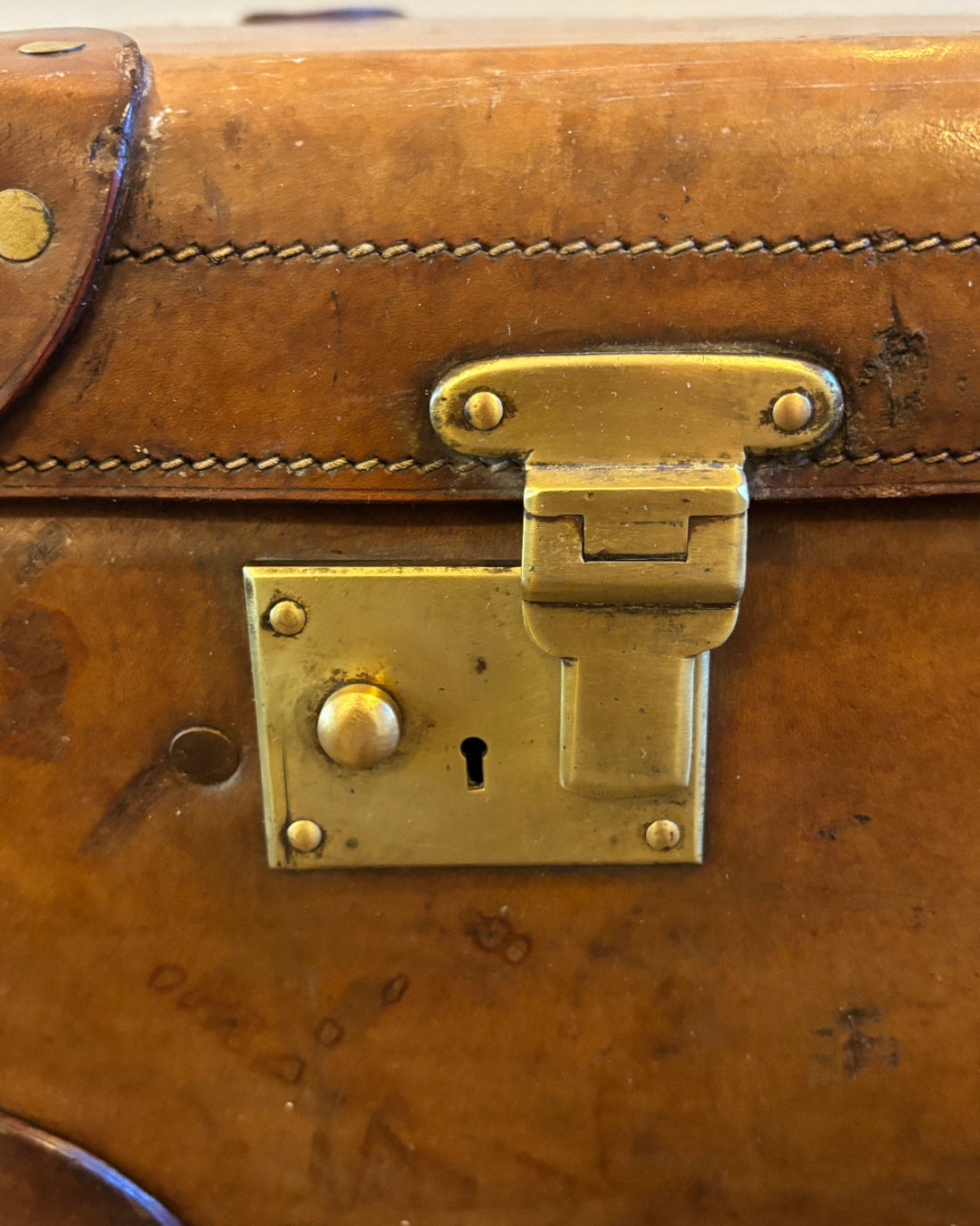 Close-up of a brass latch on a brown leather suitcase