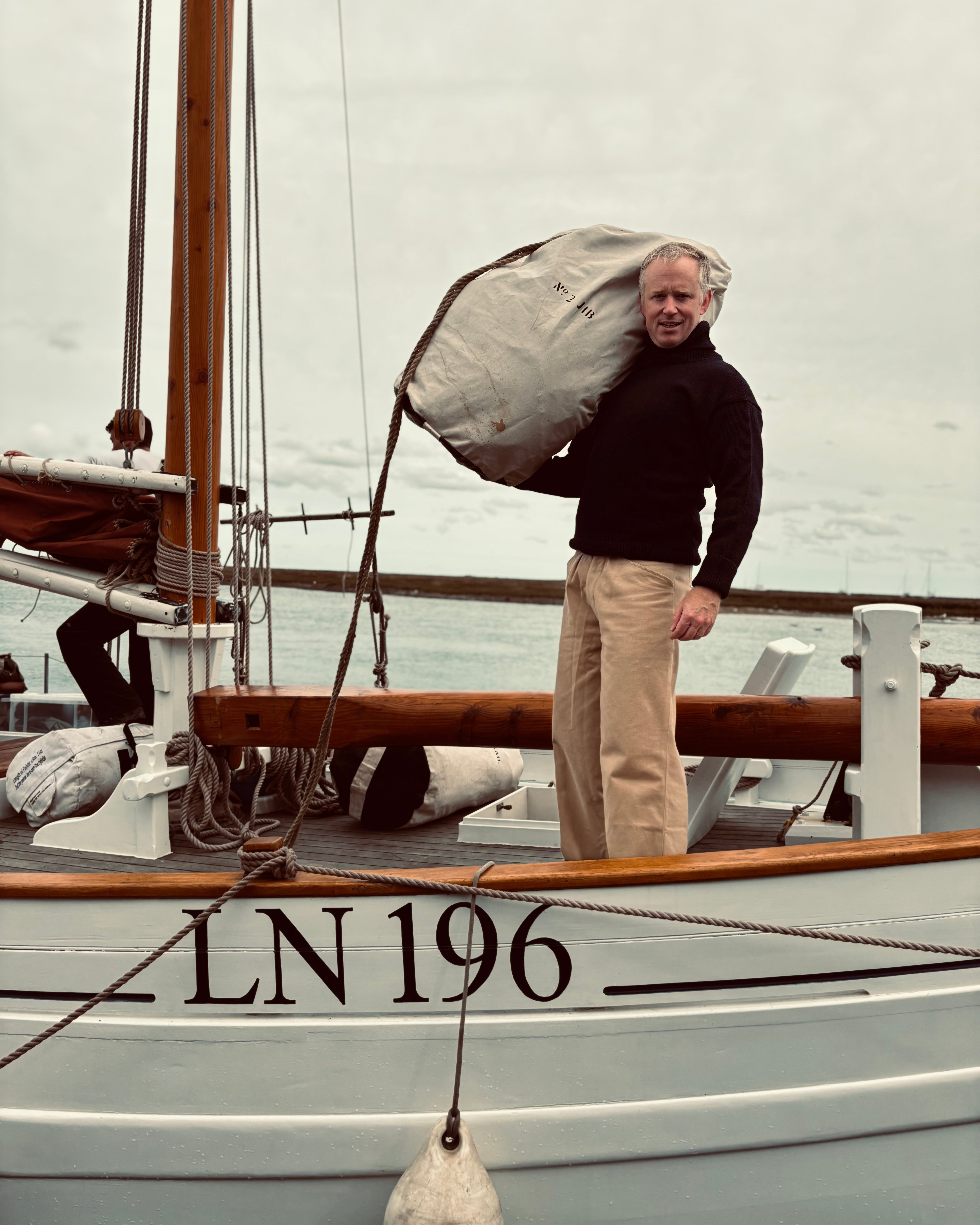Man standing on a boat named 'LN 196' with a white background