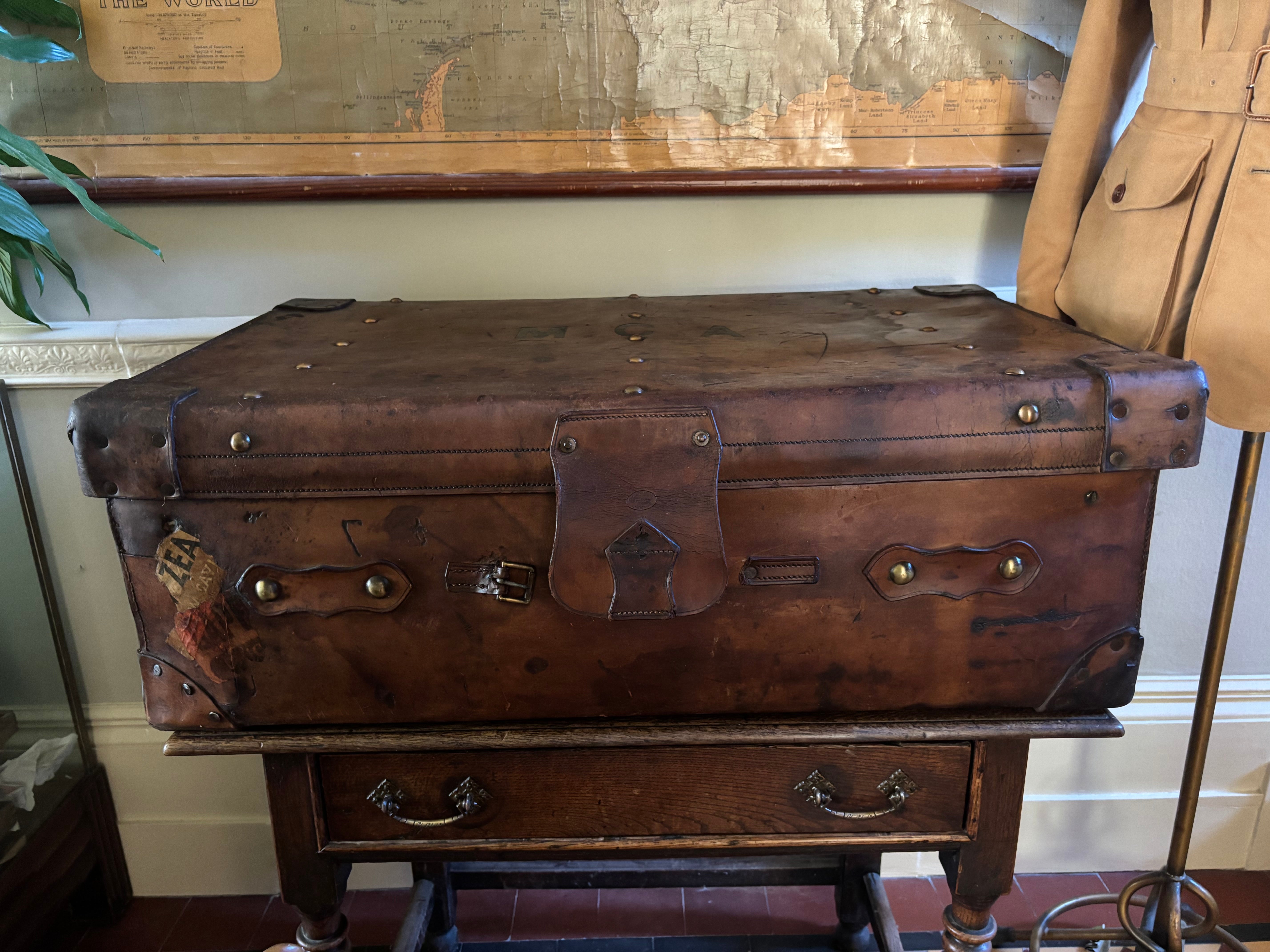 Vintage leather trunk on a wooden stand with a world map in the background