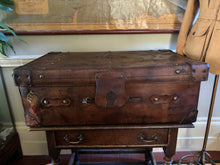 Vintage leather trunk on a wooden stand with a world map in the background