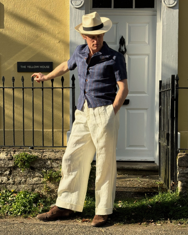 Man in a panama hat wearing a 1930s summer short sleeve linen shirt and wide legged trousers