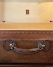 Close-up of a brown leather suitcase handle with a blurred background