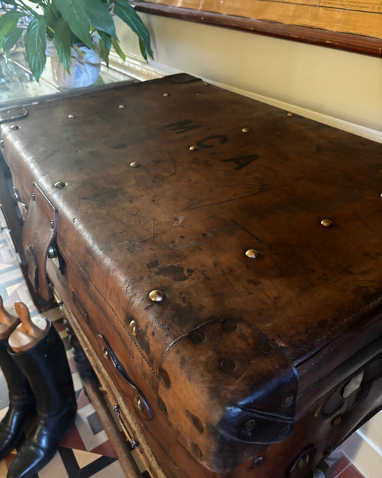 Vintage leather trunk on a wooden stand with a world map in the background
