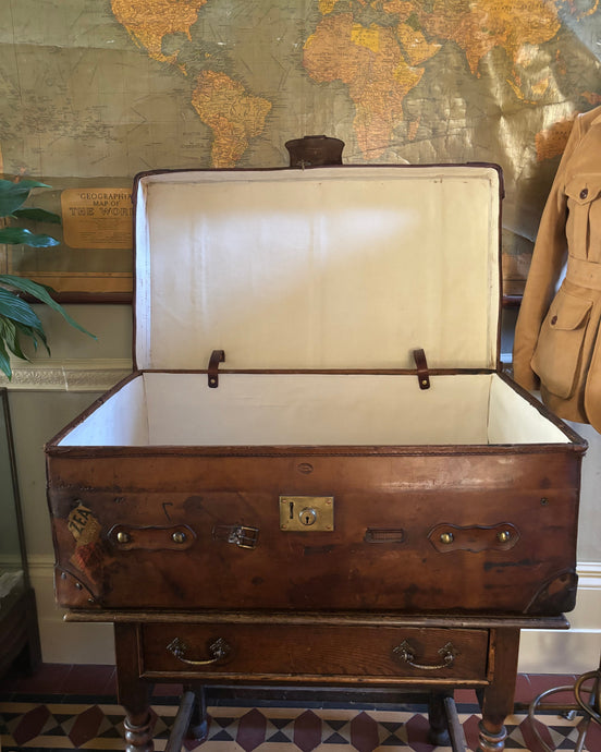Vintage leather trunk on a wooden stand with a world map in the background