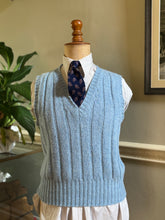 1930's Light blue knitted vest on a mannequin with a white shirt and dark tie, against a neutral indoor background.