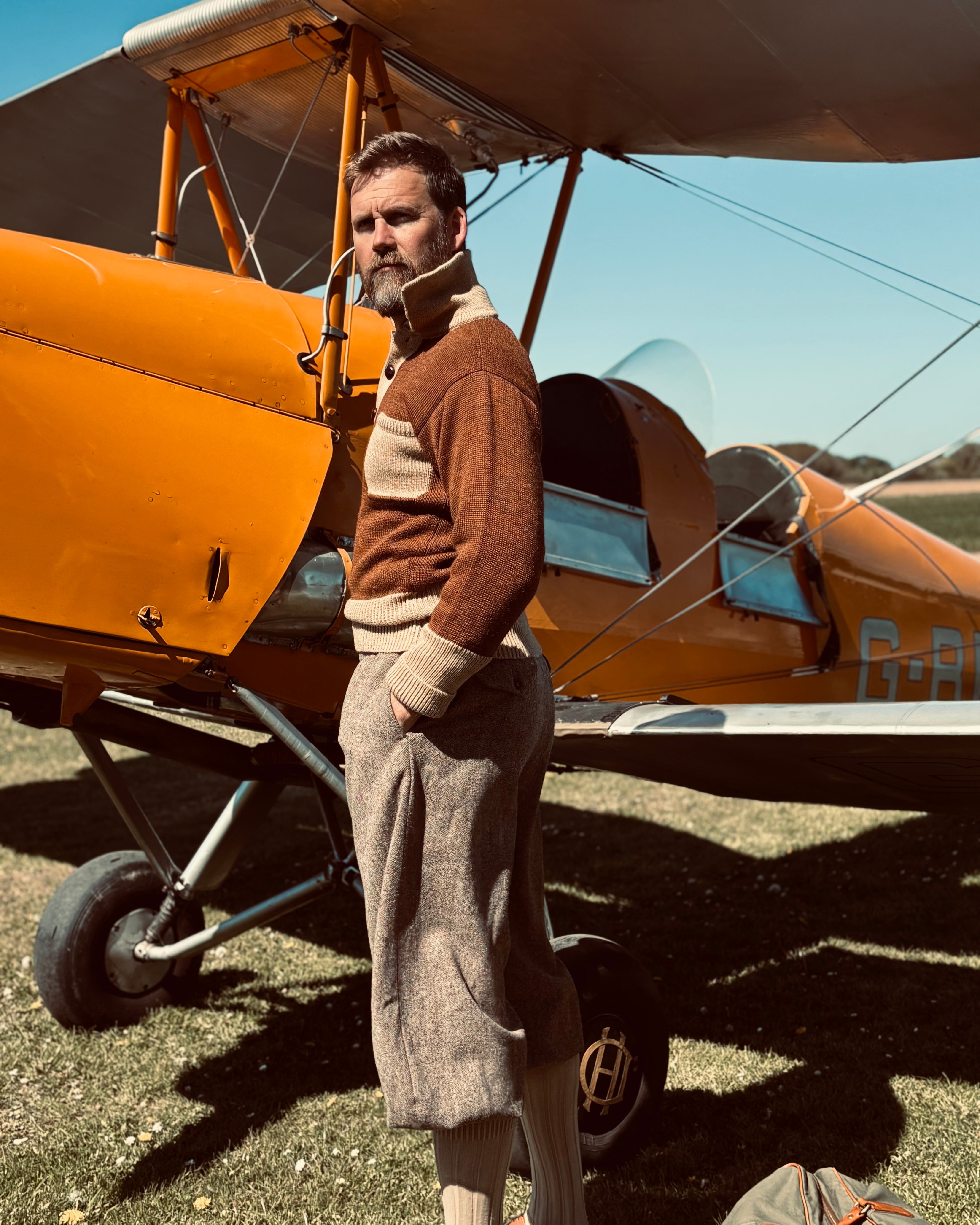 Man standing next to a vintage biplane on a sunny day