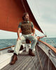Man sitting on a sailboat deck with a sail in the background