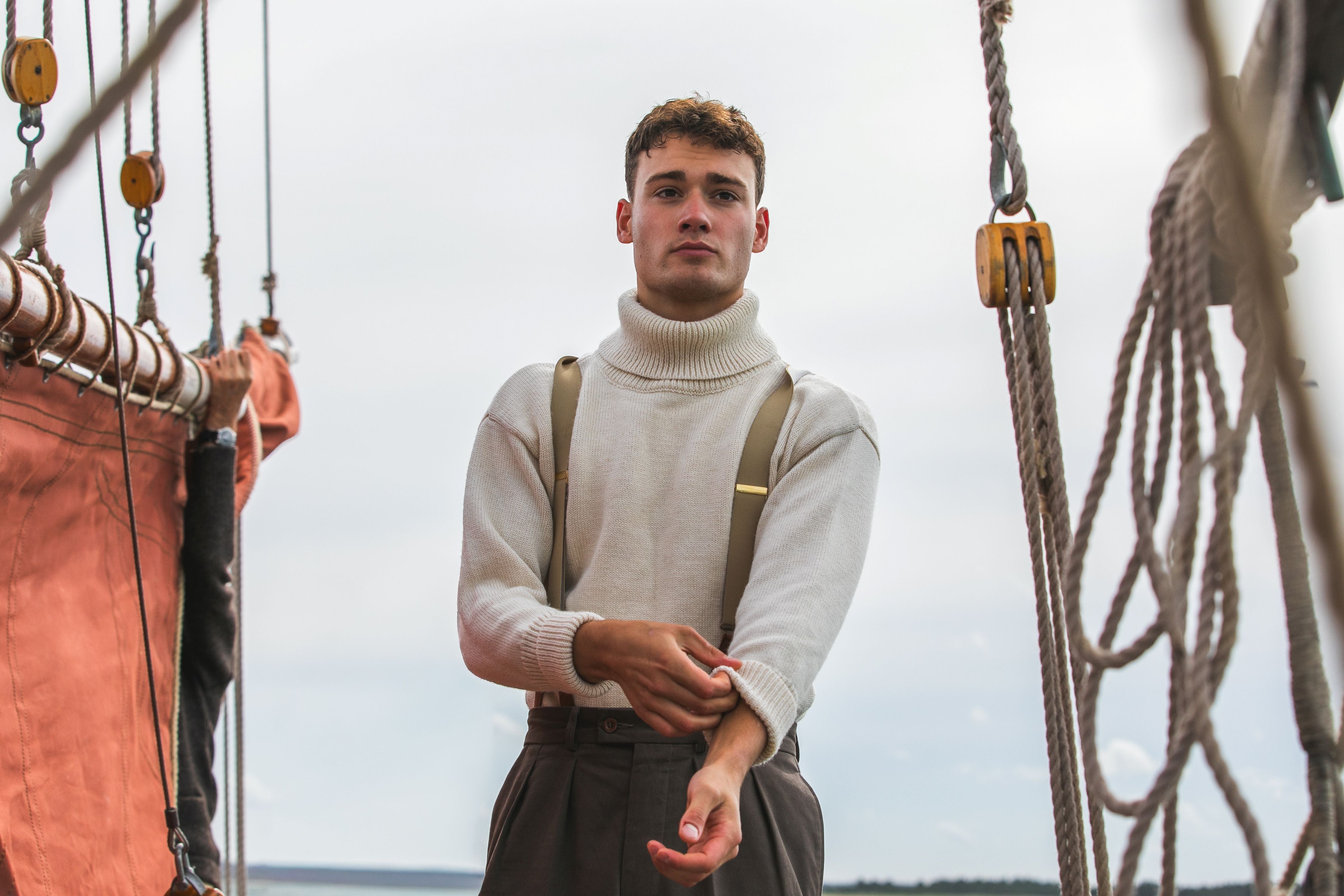 Man standing on a ship with ropes and rigging in the background