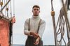 Man standing on a ship with ropes and rigging in the background