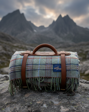Plaid blanket with brown leather straps on a rock with mountains in the background