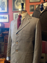 A vintage 1940s style brown dogtooth tweed suit on a mannequin, featuring a jacket with 1940s lapels and corozo buttons, and trousers with double pleats.